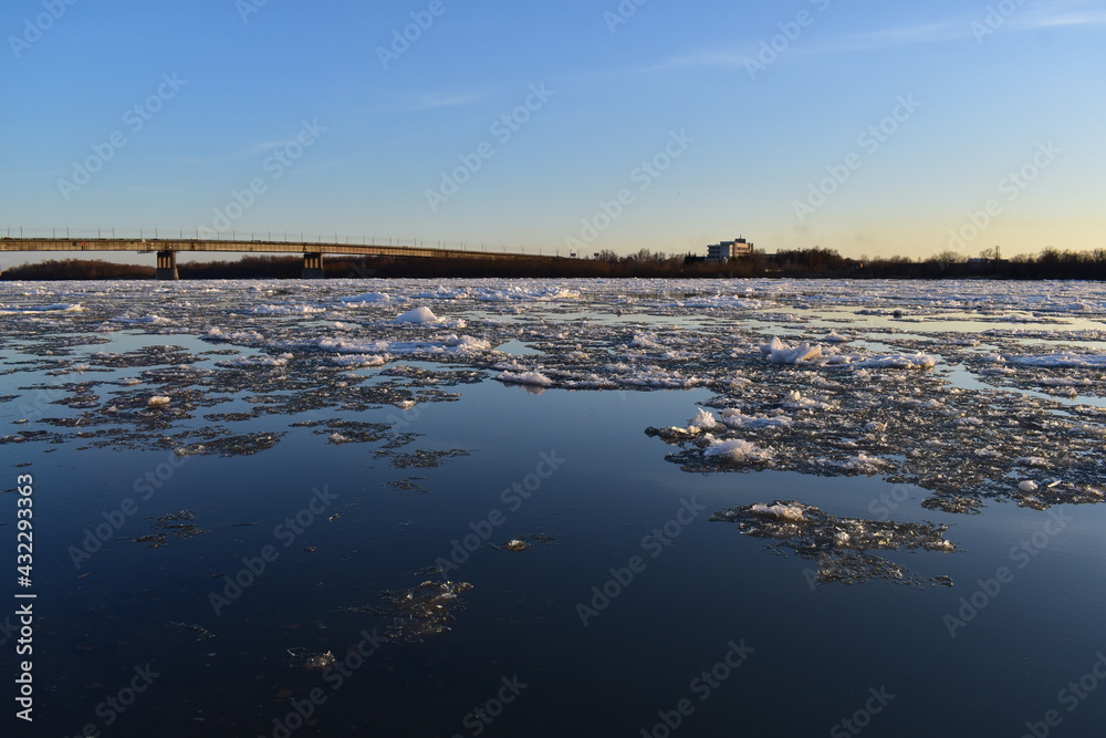 Evening spring landscape. View from the river bank on the ice drift at sunset.