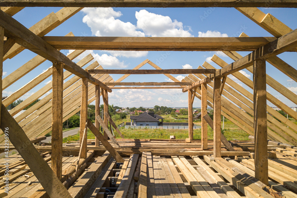 Aerial view of unfinished house with wooden roof frame structure under construction.