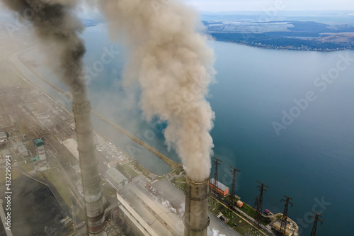 Aerial view of coal power plant high pipes with black smoke moving up polluting atmosphere.