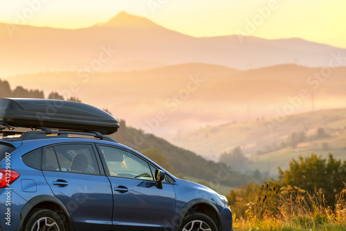 Fototapeta Naklejka Na Ścianę i Meble -  SUV car with roof rack luggage container for off road travelling parked at roadside at sunset.
