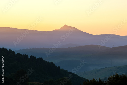 Beautiful mountain landscape with hazy peaks and foggy valley at sunset.