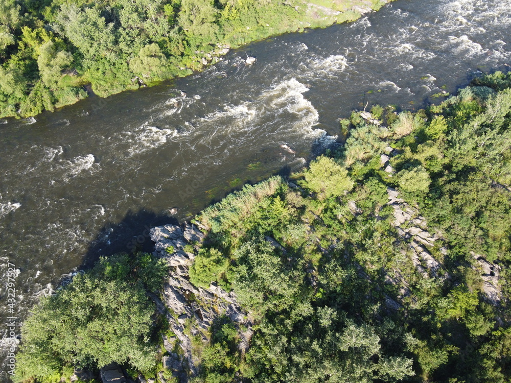 Picturesque river rapids on the Southern Bug. Rapid flow of the river over rocky terrain, landscape from a bird's eye view. Picturesque river rapids on the Southern Bug. Rapid flow of the river over rocky terrain, landscape from a bird's eye view.
