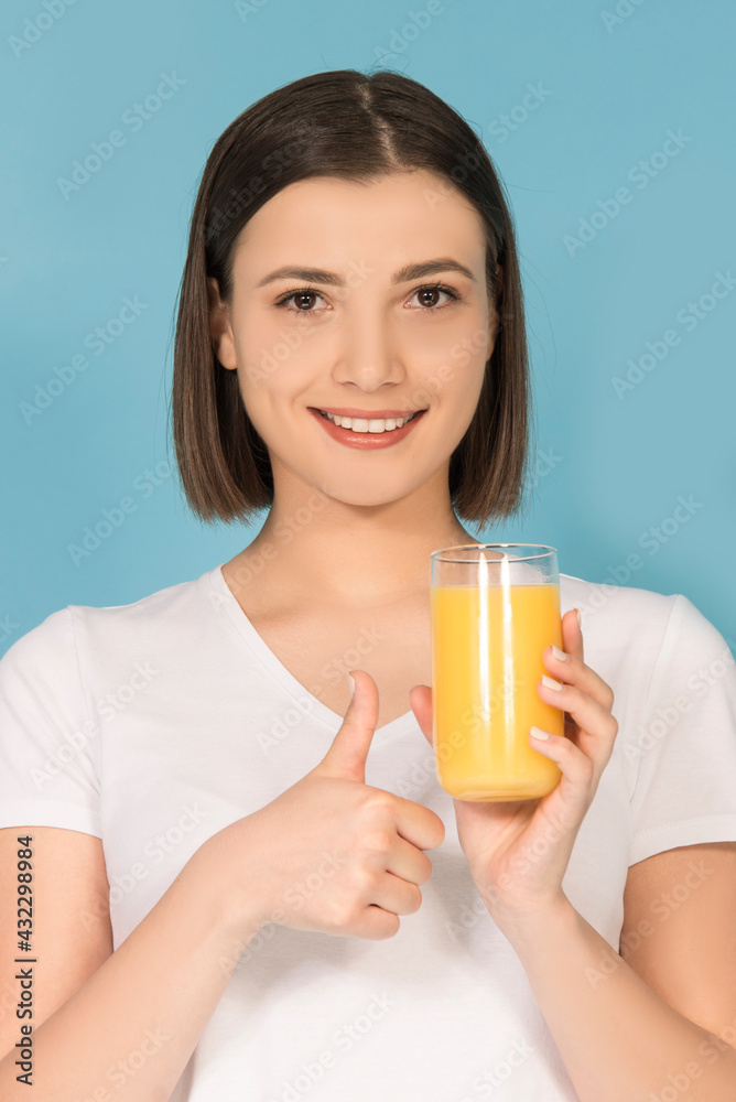 Young Caucasian woman drinking fresh orange juice isolated on blue background Young Caucasian woman drinking fresh orange juice isolated on blue background