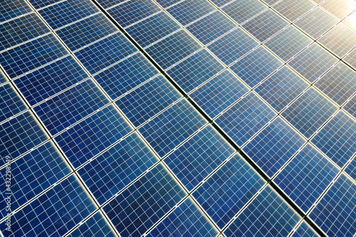 Aerial view of surface of blue photovoltaic solar panels mounted on building roof for producing clean ecological electricity. Production of renewable energy concept.