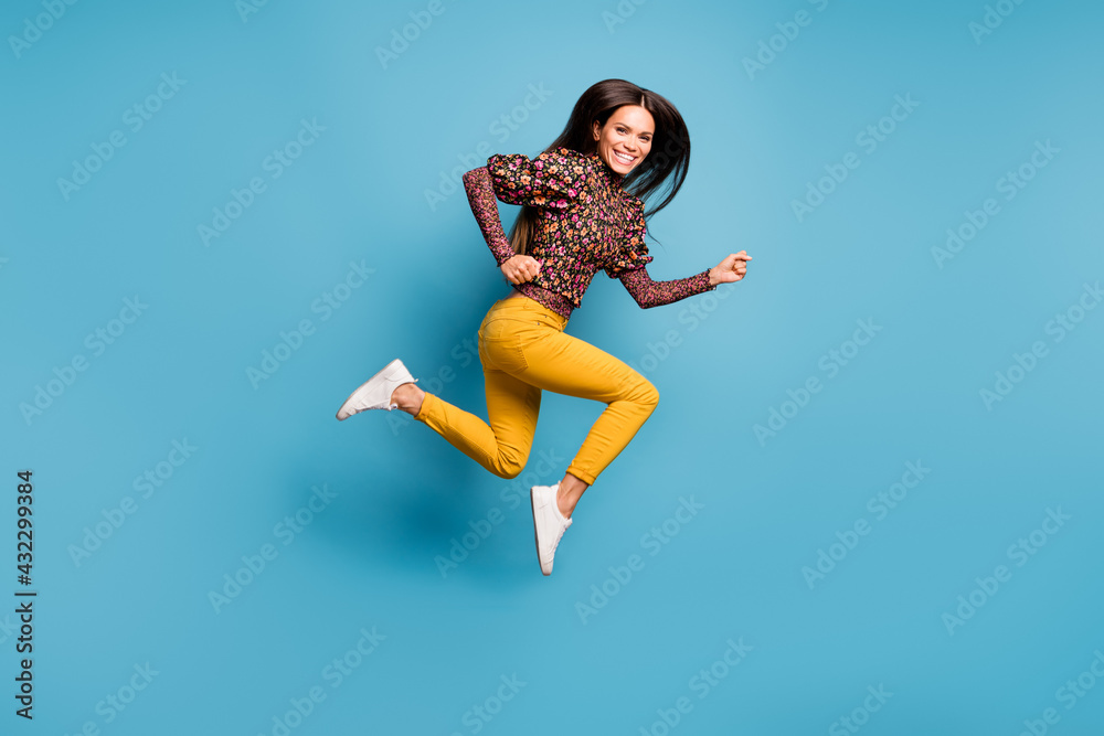 Profile side full size photo of young cheerful attractive smiling woman running fast isolated on blue color background Profile side full size photo of young cheerful attractive smiling woman running fast isolated on blue color background