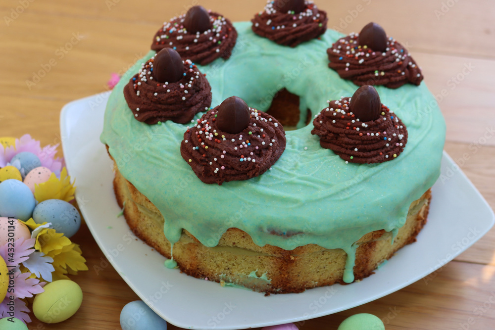Easter chiffon cake with cholcolate nests decoration on green glaze on a plate on wooden table Easter chiffon cake with cholcolate nests decoration on green glaze on a plate on wooden table