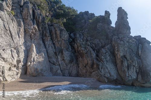 Small picturesque beach surrounded by rocks, clear turquoise water and morning light haze, Albania. Travel theme, beautiful nature