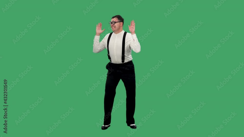 Portrait of a man looking at the camera, waving his arms raised and smiling happily. A man in a white shirt with suspenders and glasses with thick lenses in the studio on a green screen. Slow motion. Portrait of a man looking at the camera, waving his arms raised and smiling happily. A man in a white shirt with suspenders and glasses with thick lenses in the studio on a green screen. Slow motion.