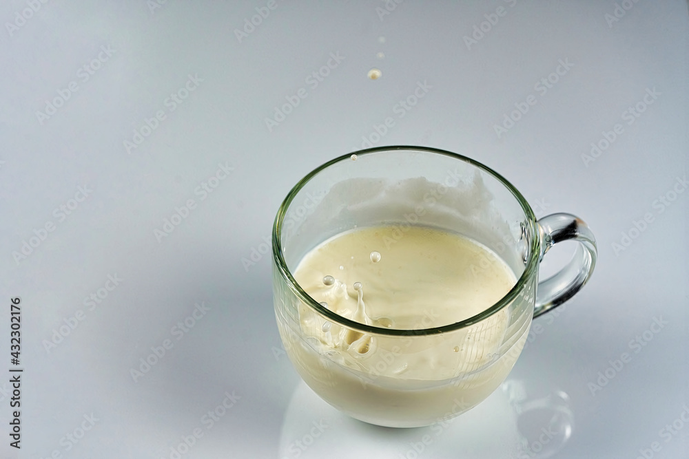 Splash of milk in a transparent glass mug Splash of milk in a transparent glass mug