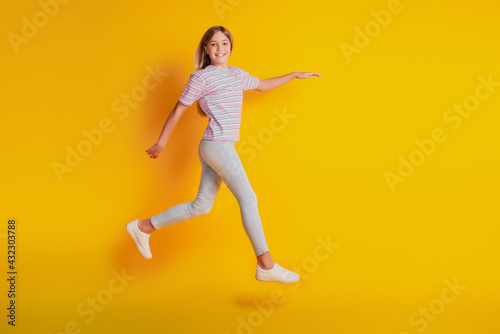 Cheerful girl jumping running isolated over yellow background