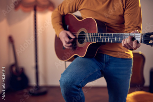 Male musician playing acoustic guitar on the amplifier in retro vintage room.