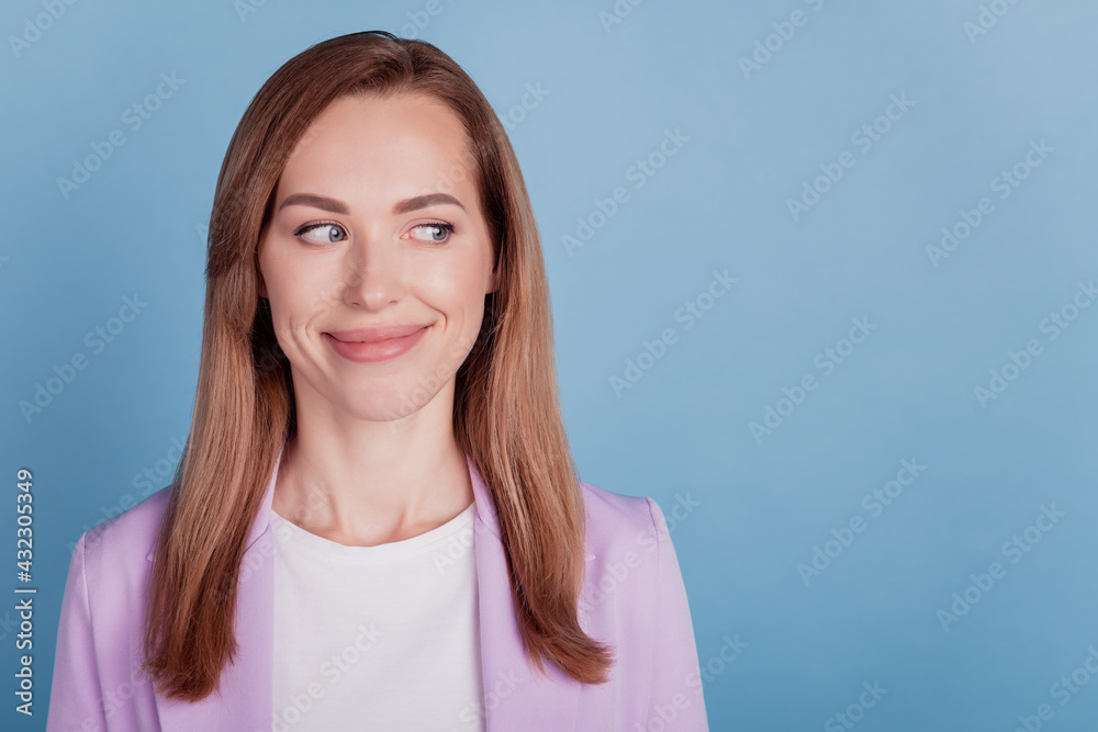 Close-up of a woman smilinglook side empty space on blue wall Close-up of a woman smilinglook side empty space on blue wall