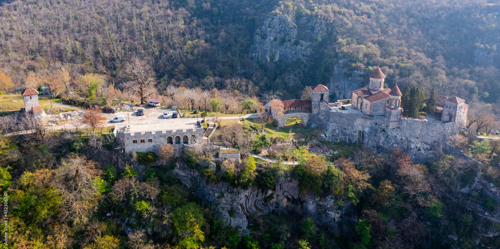 Picturesque aerial view of Georgian Orthodox Motsameta monastery on stone cliff covered with forest located near Kutaisi at Imereti region on sunny spring day