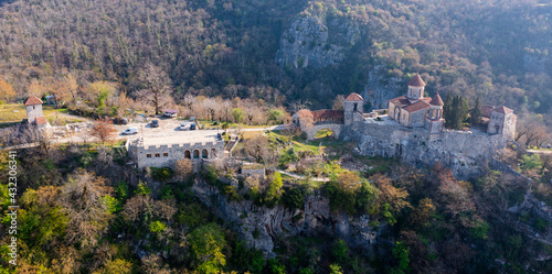 Picturesque aerial view of Georgian Orthodox Motsameta monastery on stone cliff covered with forest located near Kutaisi at Imereti region on sunny spring day