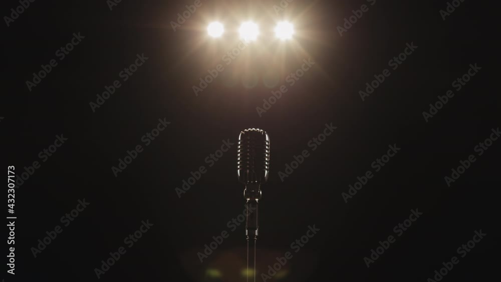 The man is approaching the microphone. There is a retro microphone on the stage. The singer is going to the microphone. The spotlight is shining on him. 4K