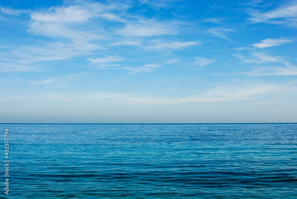 turquoise blue sea horizon with two thirds of blue sky with white clouds, background with copy space turquoise blue sea horizon with two thirds of blue sky with white clouds, background with copy space
