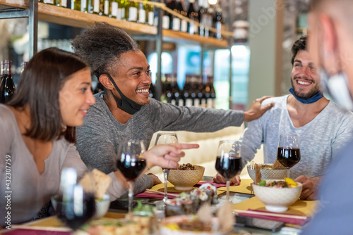Young afro american man having fun with friends at restaurant  group of people having a party after been vaccinated  happiness for the end of pandemic period