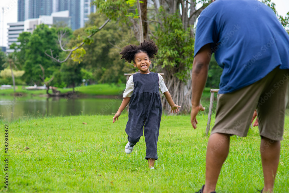 Happy mixed race family in park. African father playing and hugging together with little daughter at public park. Dad and child girl kid enjoy and having fun outdoor lifestyle activity in summer. Happy mixed race family in park. African father playing and hugging together with little daughter at public park. Dad and child girl kid enjoy and having fun outdoor lifestyle activity in summer.