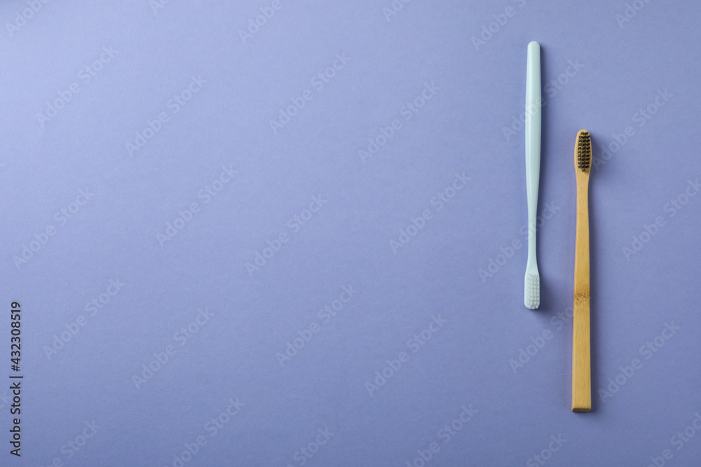 Eco friendly and plastic toothbrushes on violet background Eco friendly and plastic toothbrushes on violet background