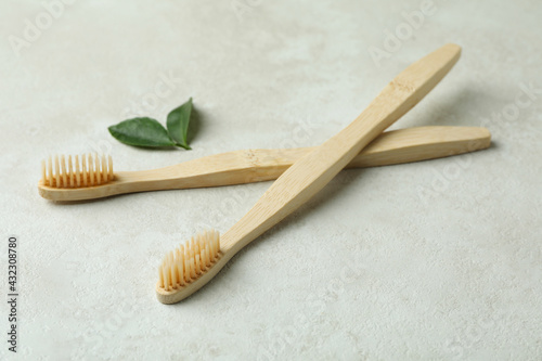 Eco friendly toothbrushes and leaves on white textured background