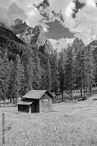 Alte hölzerne Almhütte auf einer Bergwiese mit den Gipfeln der Sextener Dolomiten dahinter, schwarzweiß Foto, Pustertal, Alpen, Südtirol, Italien 