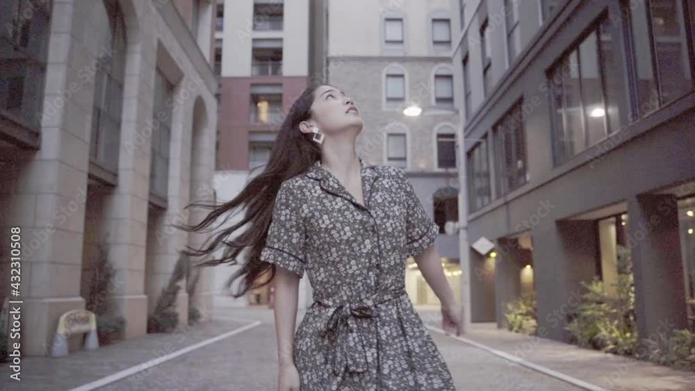 髪をなびかせながら街を見回す若い女性 髪をなびかせながら街を見回す若い女性