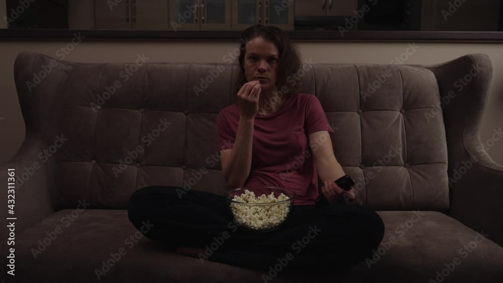 switch channel to tv using driver. woman with a bowl of popcorn switch channel to tv using driver. woman with a bowl of popcorn