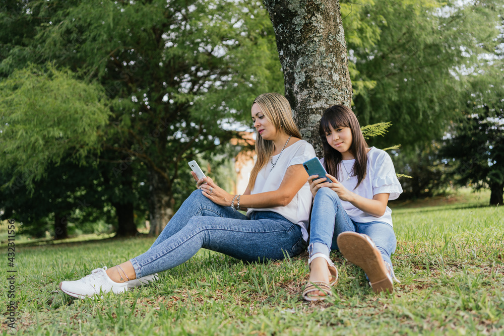 Mother and daughter sitting under a tree.