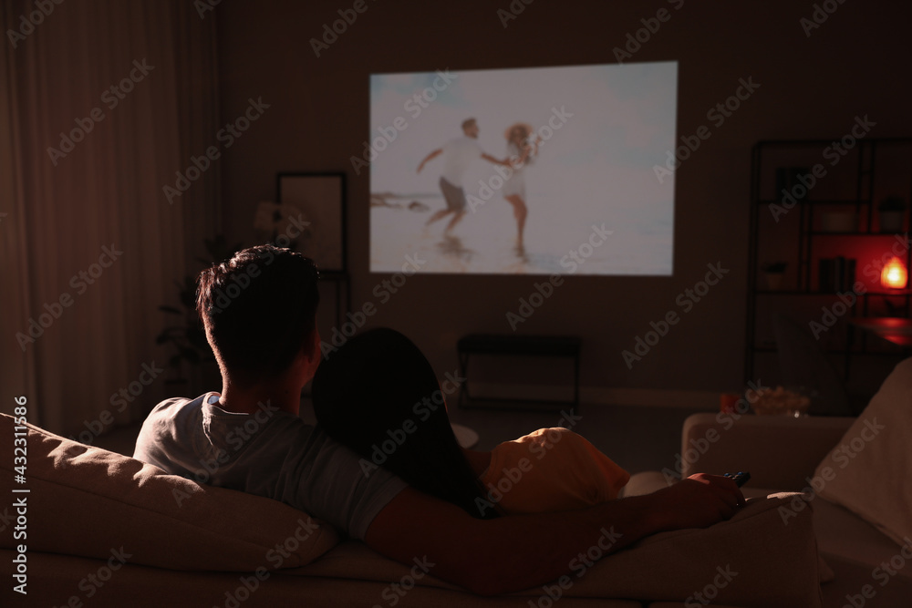 Couple watching movie on sofa at night, back view Couple watching movie on sofa at night, back view