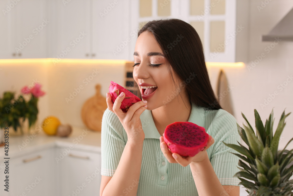 Young woman with fresh pitahaya in kitchen, space for text. Exotic fruit Young woman with fresh pitahaya in kitchen, space for text. Exotic fruit