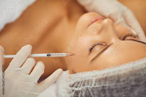 Close up of beautician hands making beauty injection in girl s face in beauty clinic.