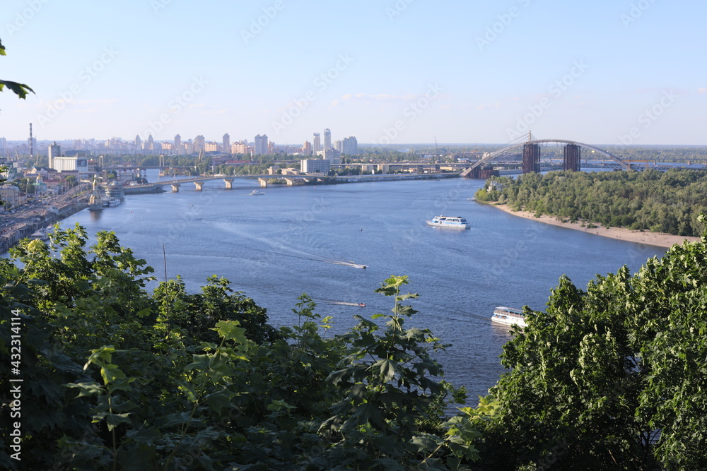 The Dnipro River in Kyiv, Ukraine. Panoramic space with green town coastline on a sunny day.