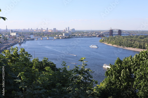 The Dnipro River in Kyiv, Ukraine. Panoramic space with green town coastline on a sunny day. © Liudmyla Leshchynets