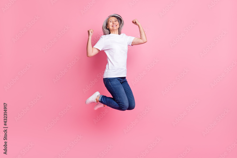 Full length body size photo of elder woman jumping up gesturing like winner overjoyed isolated pastel pink color background Full length body size photo of elder woman jumping up gesturing like winner overjoyed isolated pastel pink color background