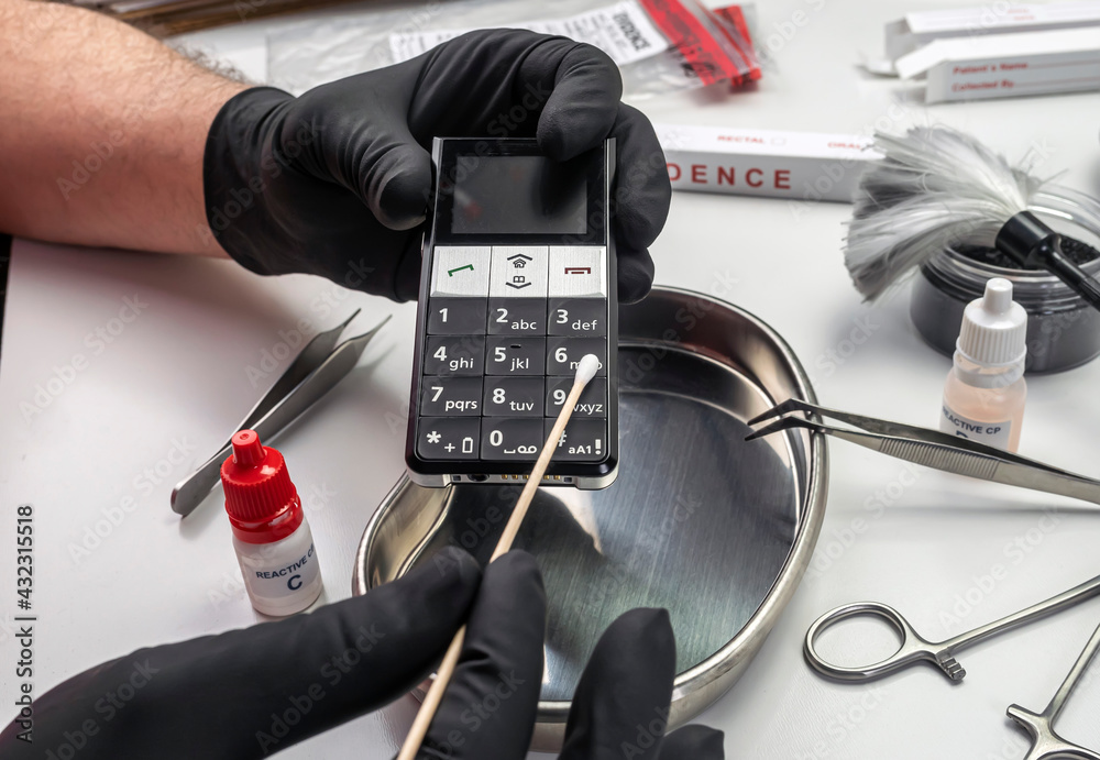 Police scientist takes DNA samples from phone involved in murder in lab, conceptual image Police scientist takes DNA samples from phone involved in murder in lab, conceptual image
