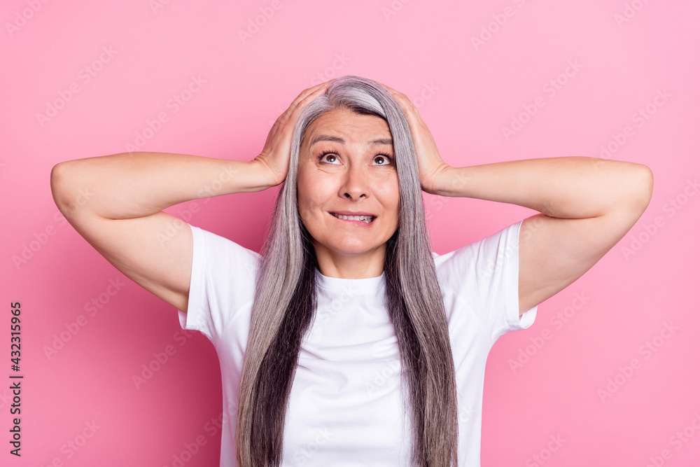 Photo portrait of grandmother with grey hair amazed touching head looking up biting lips isolated on pastel pink color background Photo portrait of grandmother with grey hair amazed touching head looking up biting lips isolated on pastel pink color background