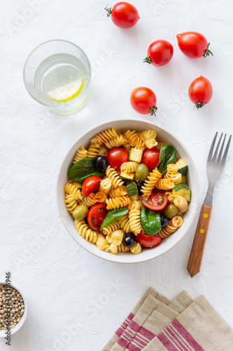Pasta salad with tomatoes, zucchini, olives and spinach. Healthy eating. Vegetarian food.
