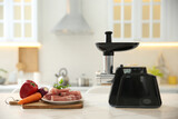 Modern meat grinder and products on white marble table in kitchen. Space for text