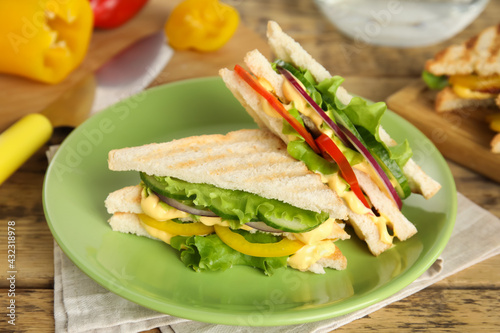 Green plate with tasty sandwiches on wooden table