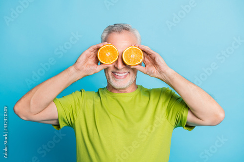 Portrait of attractive cheerful grey-haired man closing eyes with orange pieces isolated over bright blue color background