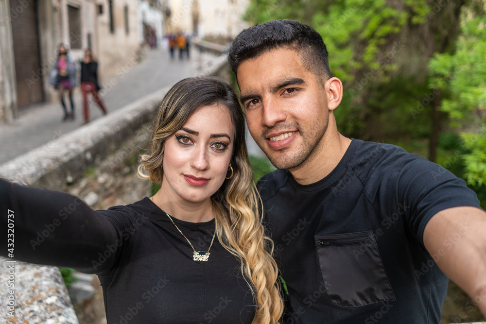 Fototapeta premium Hispanic couple in love take a selfie with their smartphone