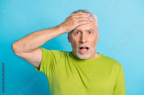 Portrait of shocked handsome man hand on forehead open mouth staring isolated on blue color background