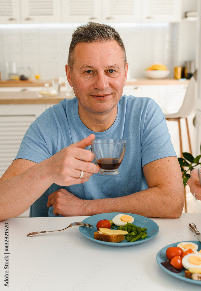 Photo of healthy senior man positive smile have dinner on the kitchen Photo of healthy senior man positive smile have dinner on the kitchen