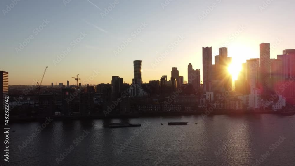 Aerial panning shot showing gigantic skyline of Canary Wharf district by sunset in London. Sunbeams shining through the skyscraper buildings. Aerial panning shot showing gigantic skyline of Canary Wharf district by sunset in London. Sunbeams shining through the skyscraper buildings.