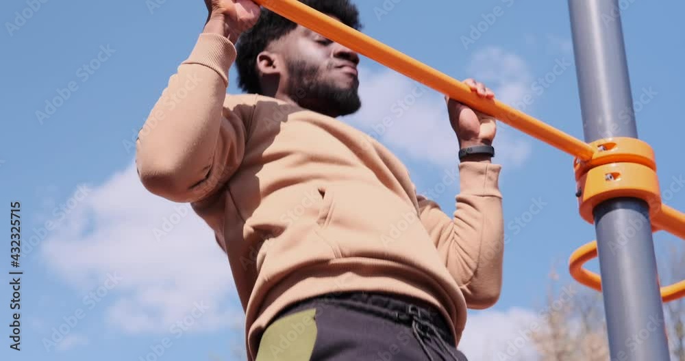 African american man doing pull ups on horizontal bar at park