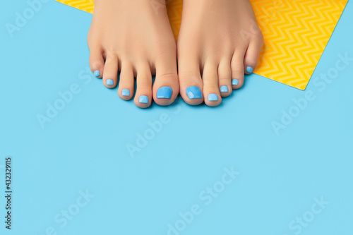 Manicure, pedicure beauty salon concept. Womans feet on blue background