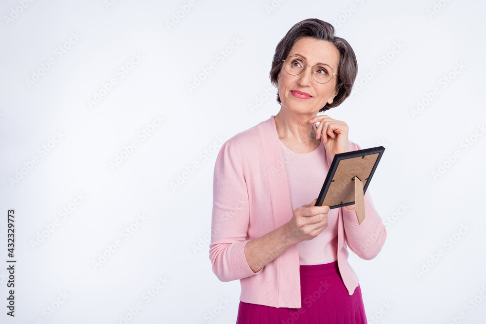 Photo of dreamy cute age woman dressed pink outfit spectacles holding photo frame looking empty space isolated white color background Photo of dreamy cute age woman dressed pink outfit spectacles holding photo frame looking empty space isolated white color background