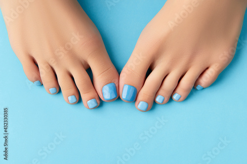 Womans feet on blue background. Beautiful fashionable summer nail design