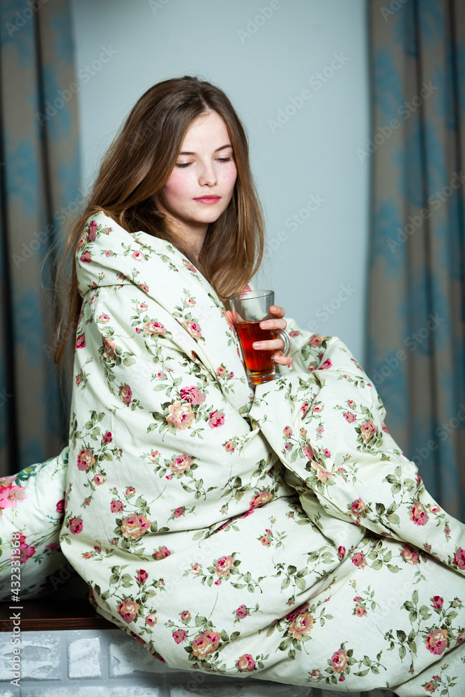 Young beautiful white woman awaking in light room. Relaxed woman lying in bed and drink tea. Good morning concept. Russian girl.