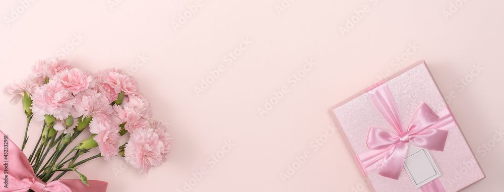 Mother's day background. Top view of gift with carnation bouquet on pink table background